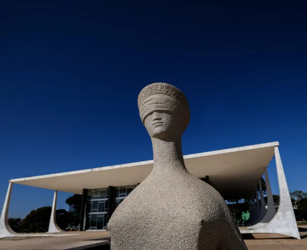 A imagem mostra a fachada do Supremo Tribunal Federal com a escultura da Justiça em primeiro plano e o prédio ao fundo. No contexto do artigo exclusivo, o elemento simboliza o centro das decisões institucionais envolvidas na proposta de reforma do Judiciário